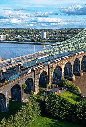 An Avanti West Coast train on a bridge going over a river.