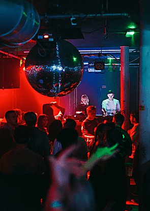 People in a club with a giant disco ball and people dancing to DJs