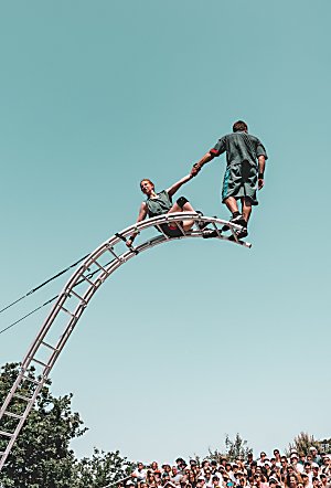 Two people on a curved ladder standing at the top of it.