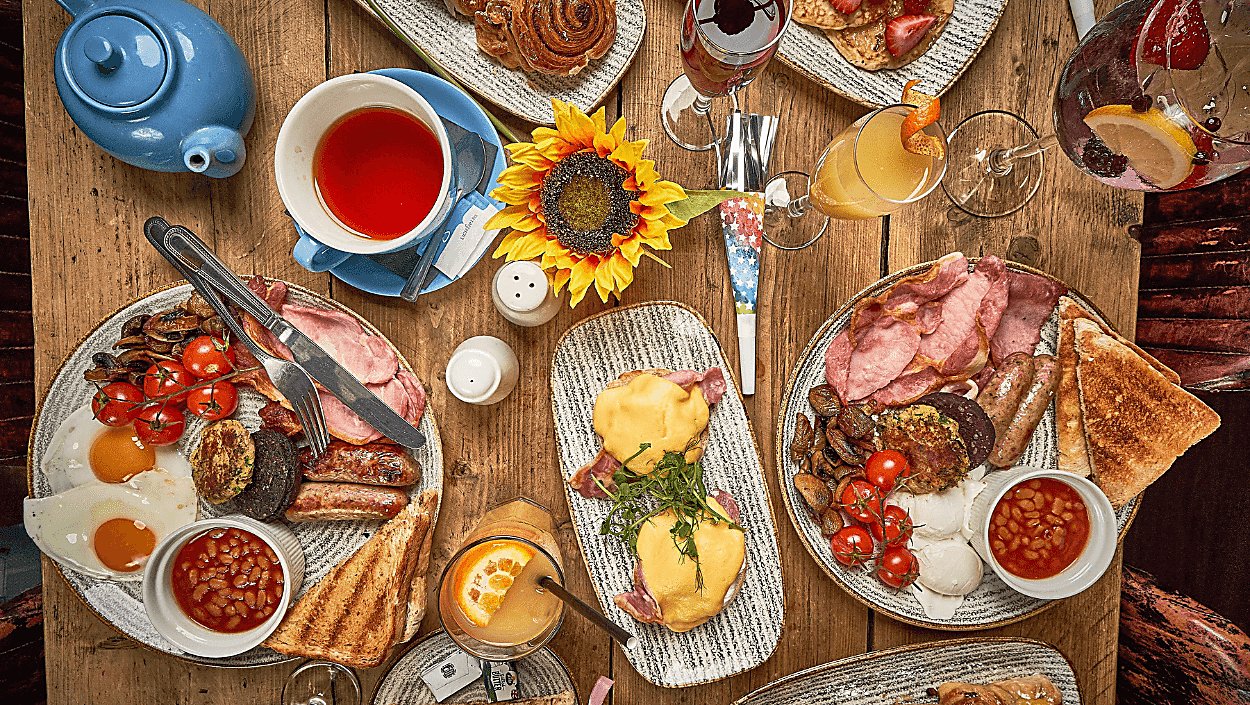 A table from a birds eye view with many places of breakfast food and drinks.