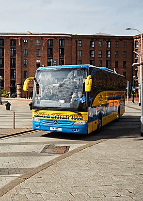 The 'Magical Mystery Tour' coach on Liverpool Albert Dock. The coach is bright yellow and green with rainbow writing on the side