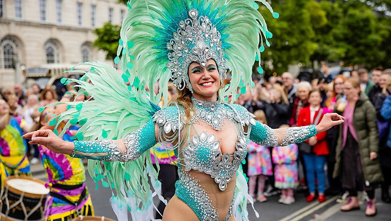 A lady dressed in carnival clothing with a large, mint green headdress