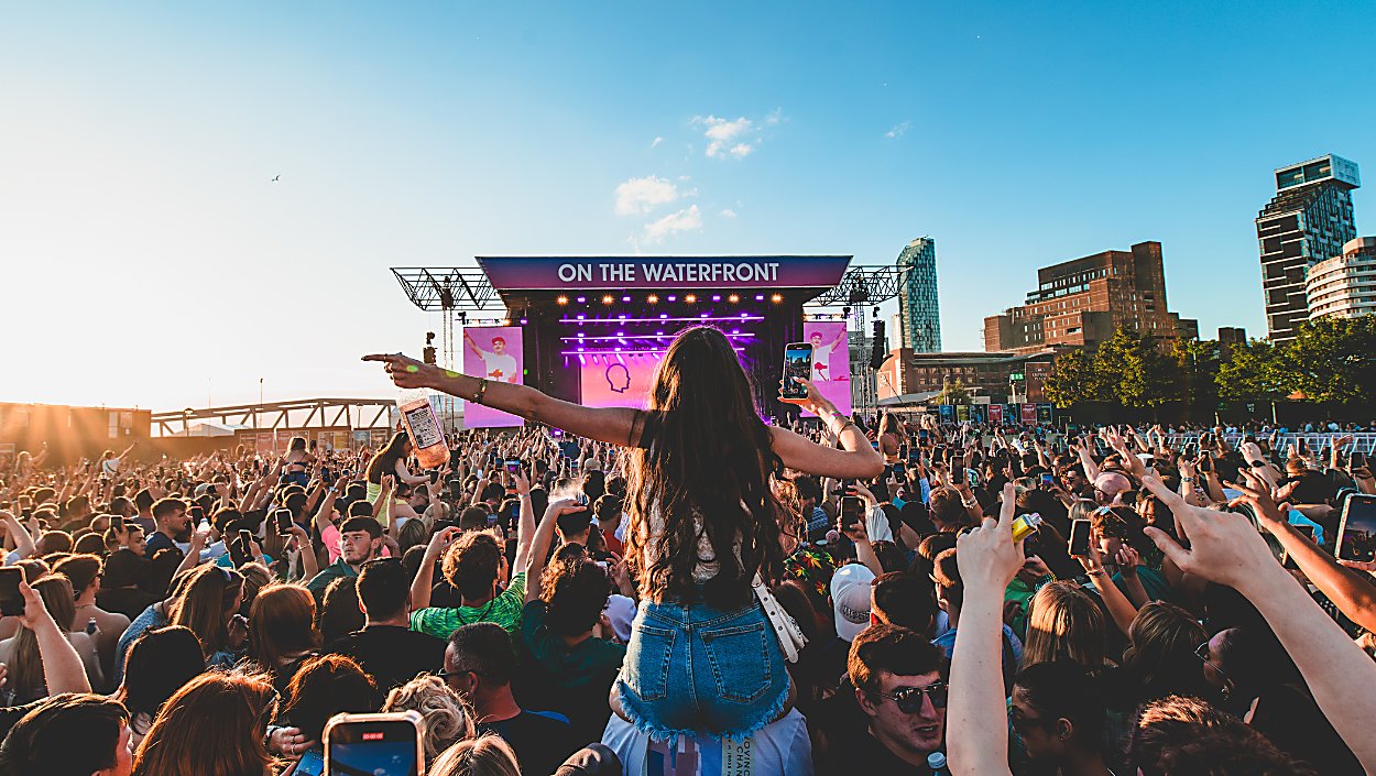 A girl on someones shoulders at a festival on Liverpool Waterfront on a sunny day
