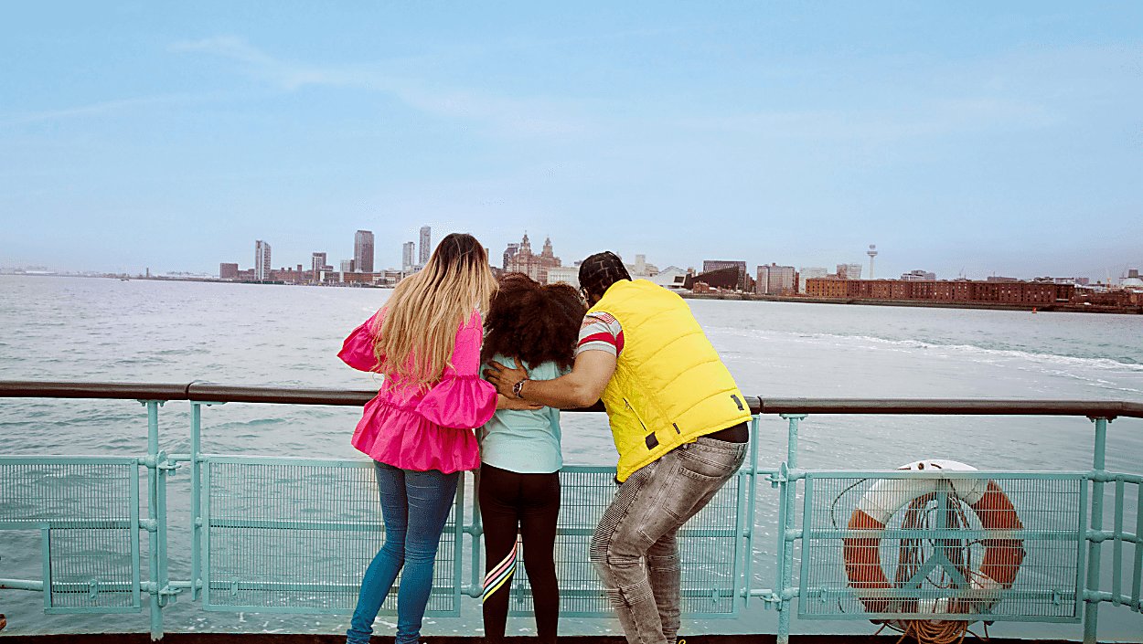 A family with a young girl in between them both look across the River Mersey