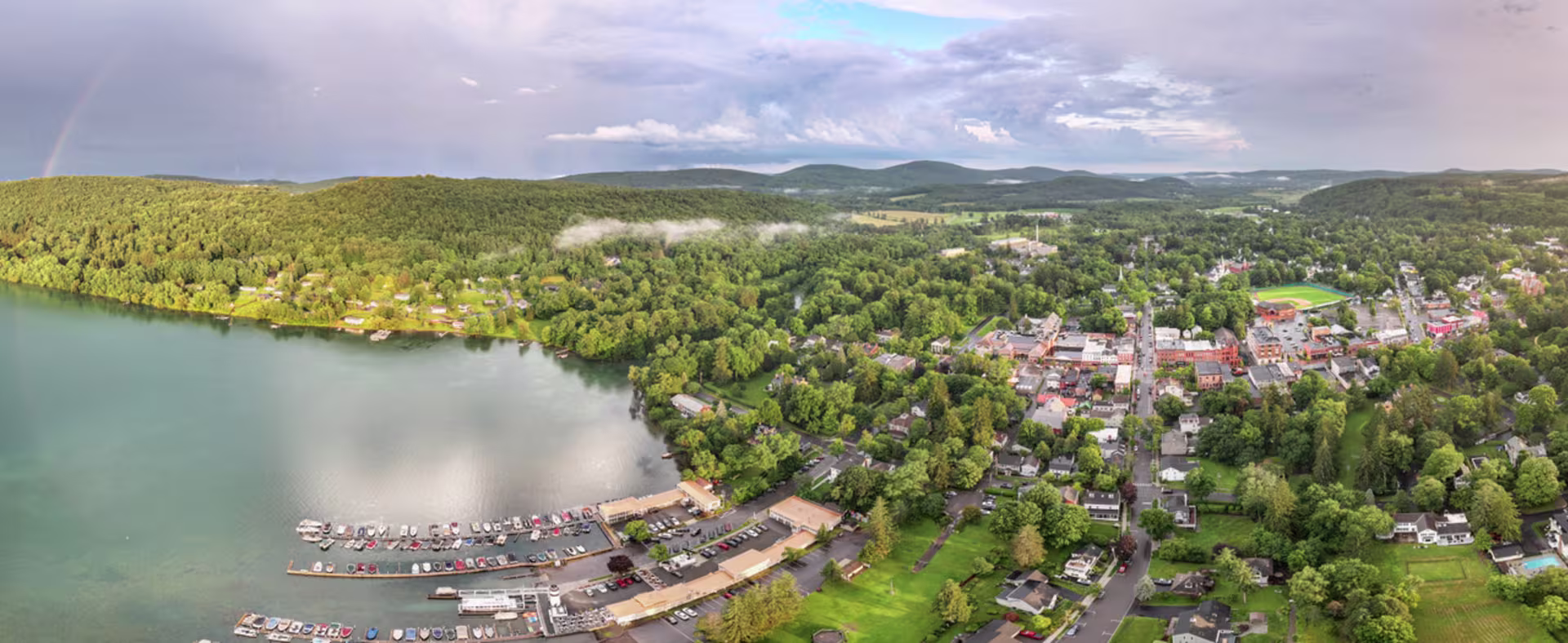 Otsego Lake at sunrise from a Cooperstown overlook, framing the village below.