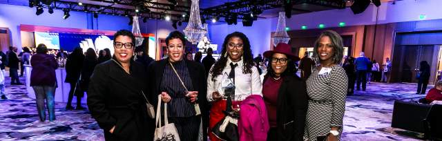 Five event attendees pose together in a ballroom at First Financial Center during a lively networking reception.
