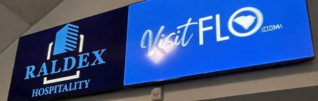 2 Tv screens with the Raldex Hospitality logo and the Visit florence logo on the concourse.