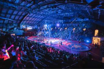 Fans viewing a Shrine Circus performance with aerial performers on the arena floor