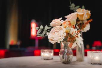 Small vase of flowers on table next to tealight candles