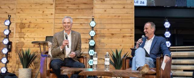 Two men speaking at e private event for their corporate company