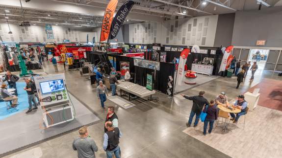 People scattered around the exhibit hall viewing various vendor booths during a large trade show