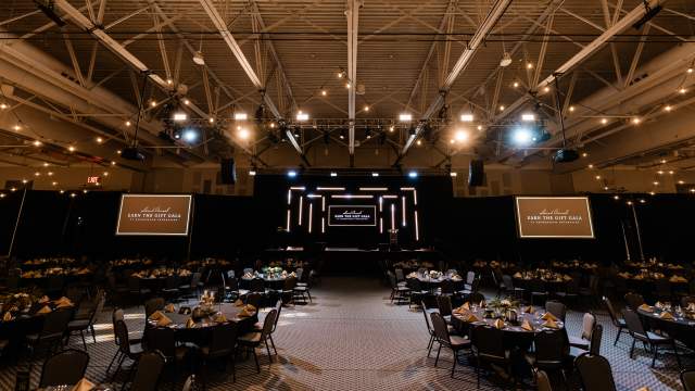 Large Exhibit Hall Set Up for Earn the Gift Gala with Stage and Round Guest Tables