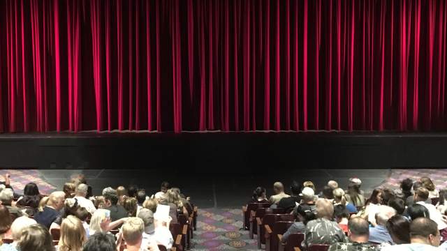 image of a closed curtain with crowd waiting