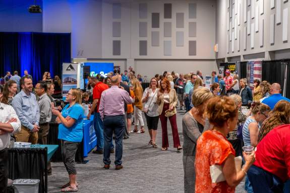 Chamber Mixer guests mingling in between various vendor booths inside of the exhibit hall