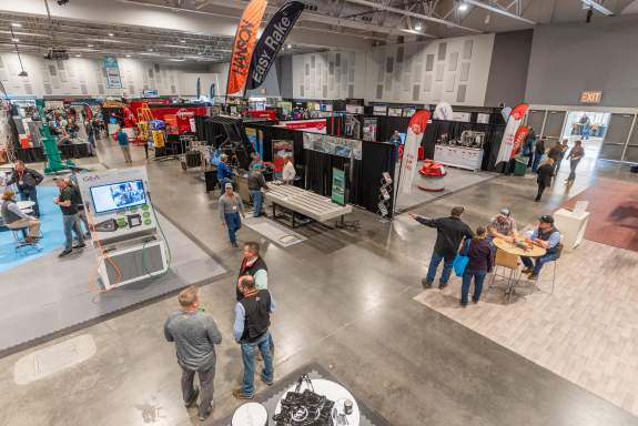 People scattered around the exhibit hall viewing various vendor booths during a large trade show