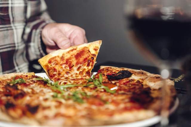 Pizza being picked up to eat in Premium, Live Lounge
