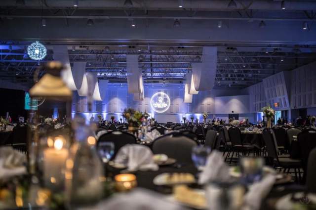 Close-Up of a Table Centerpiece with Event Monogram Light and Ceiling Drapery for Gala