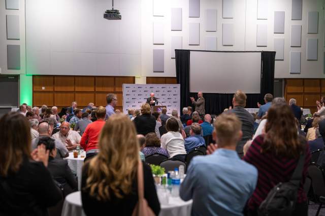 Grand Ballroom with Guests at Round Tables Listening to a Presenter