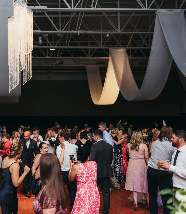 Large crowd dancing on a dance floor during a wedding reception