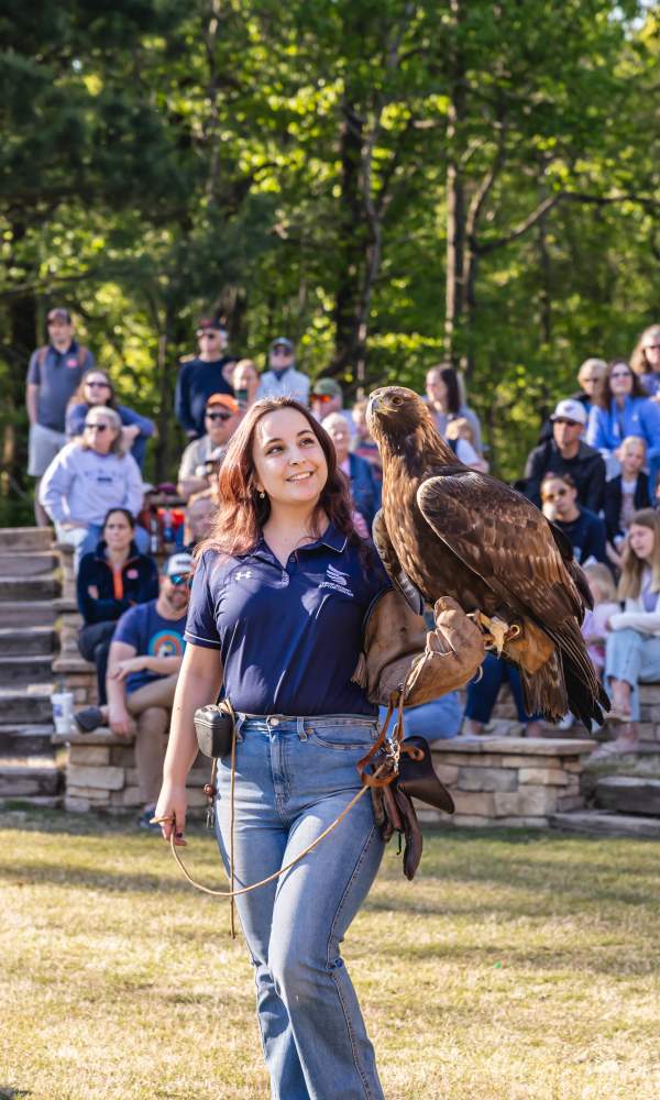 raptor center employeee standing in front of crowd with eagle