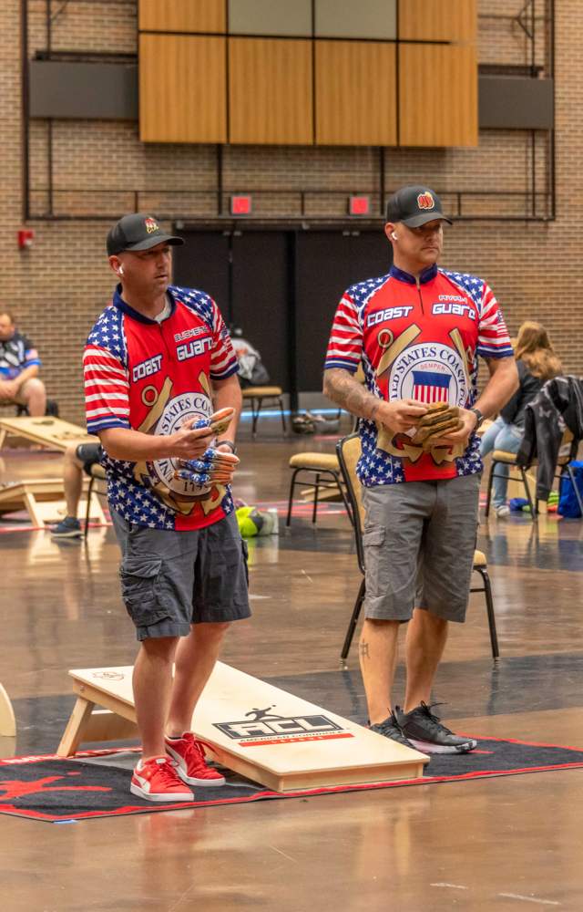 Two men throwing cornhole bags in tournament