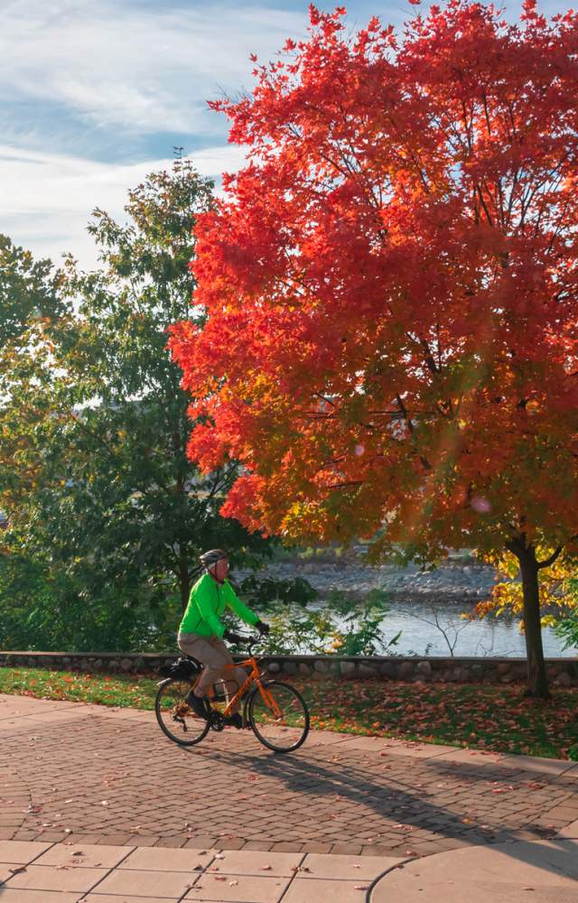 A bicyclist rides along the Mishawaka river walk in Autumn