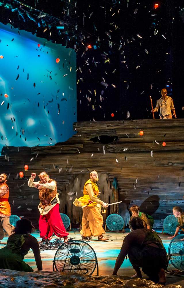 Actor on stage with confetti, fan and a boat