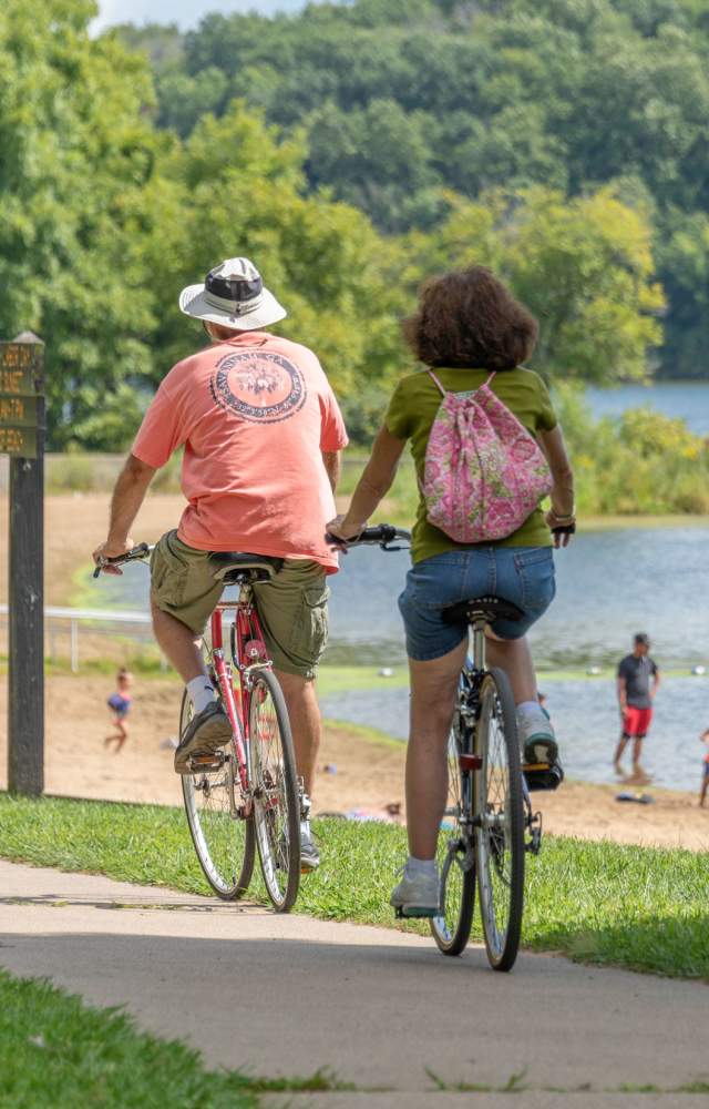Bicyclists ride past Worster Lake at Potato Creek State Park in North Liberty