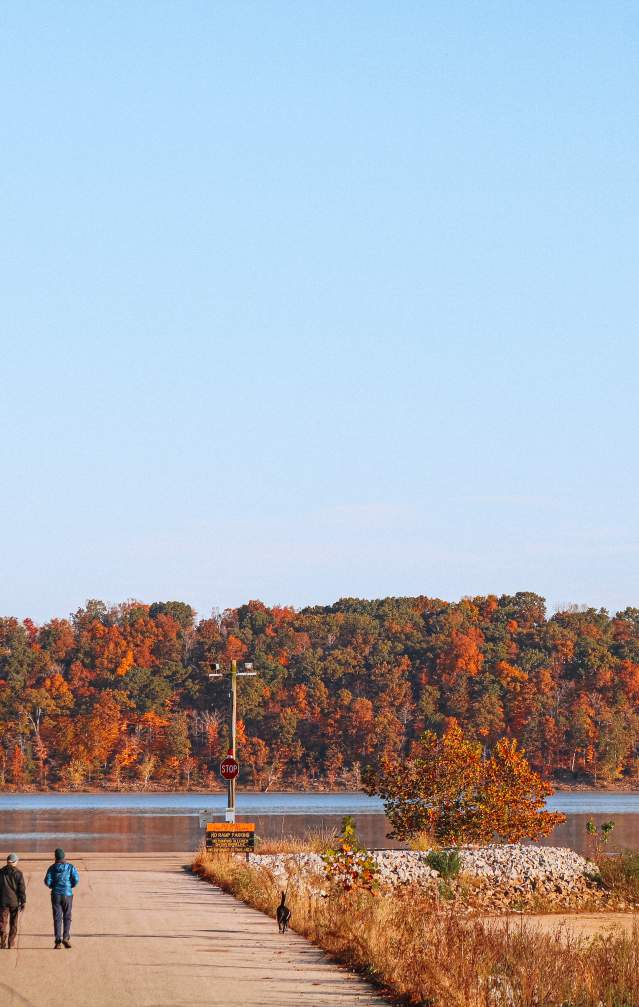 Two people walking with a dog at Monroe Lake