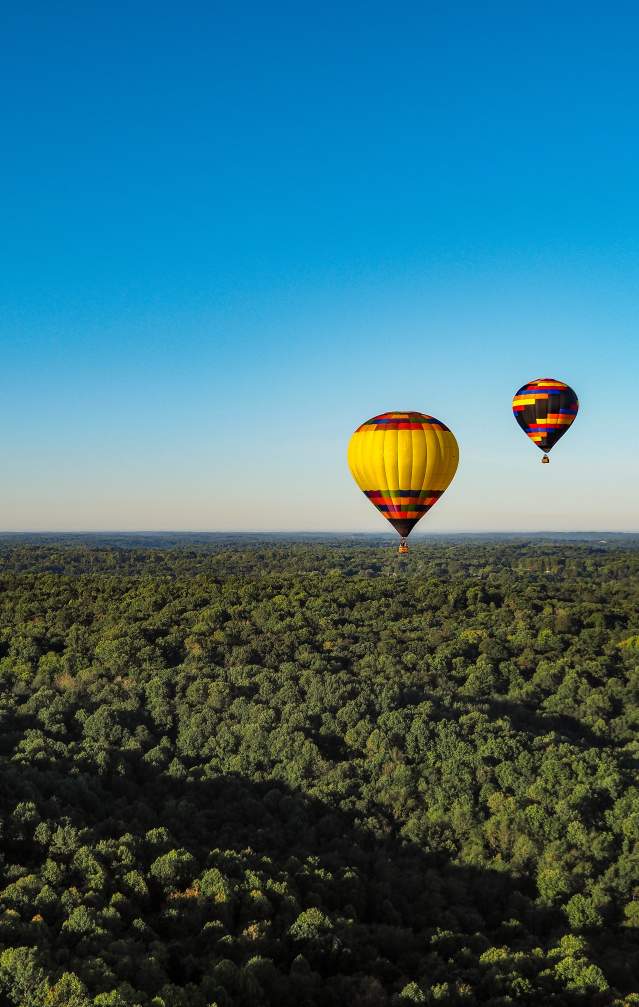 Two hot air balloons floating over Bloomington's rolling hills