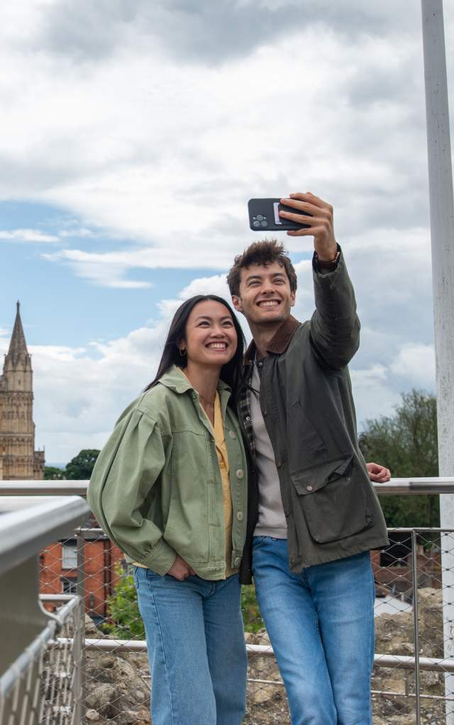 Two people having a selfie in front of Lincoln Cathedral from the walls of the castle