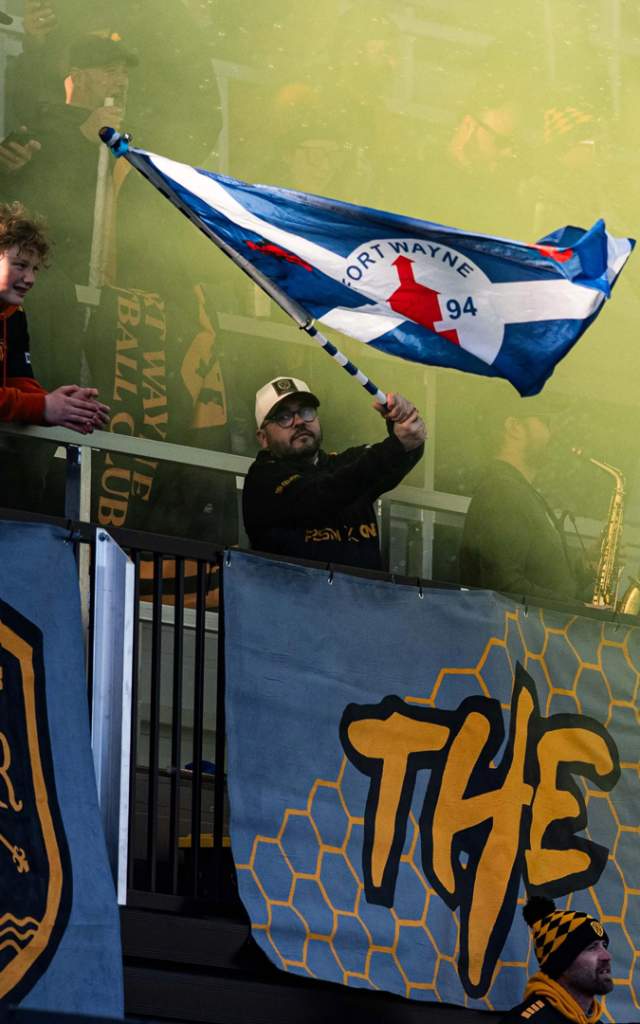 Fan waving a flag after a goal at a Fort Wayne Football Club match