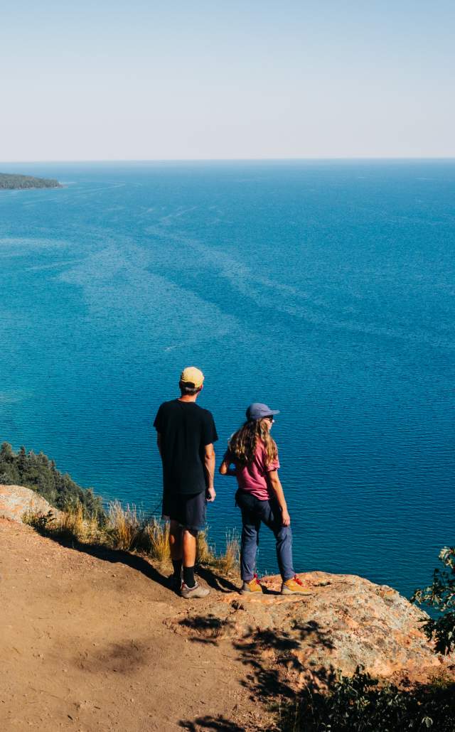 A couple standing at the edge of rocky outcropping overlooking Lake Superior, in the Upper Peninsula of Michigan
