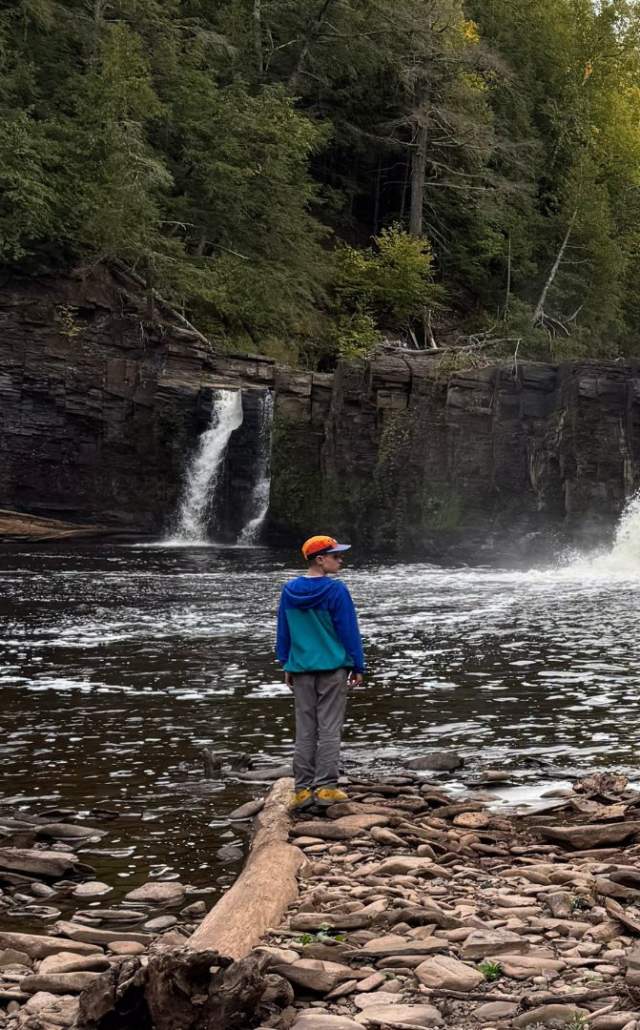 A boy exploring at Manabezho Falls in the Upper Peninsula of Michigan