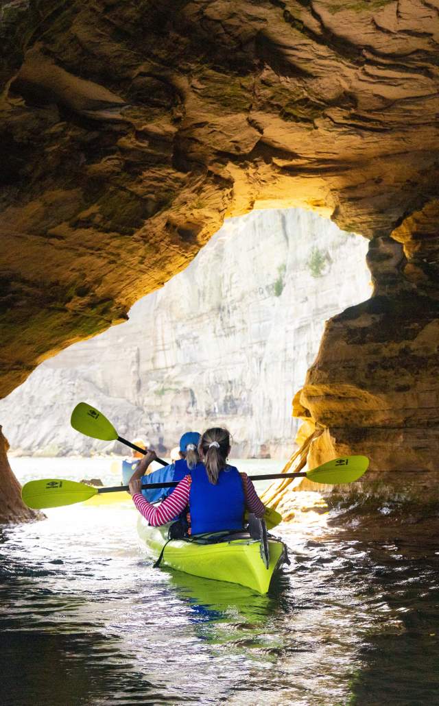 Two individuals kayaking in a sea cave in Pictured Rocks National Lakeshore.