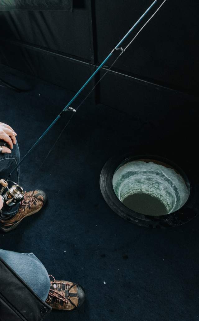 A woman ice fishing inside a fishing shack in the Upper Peninsula of Michigan