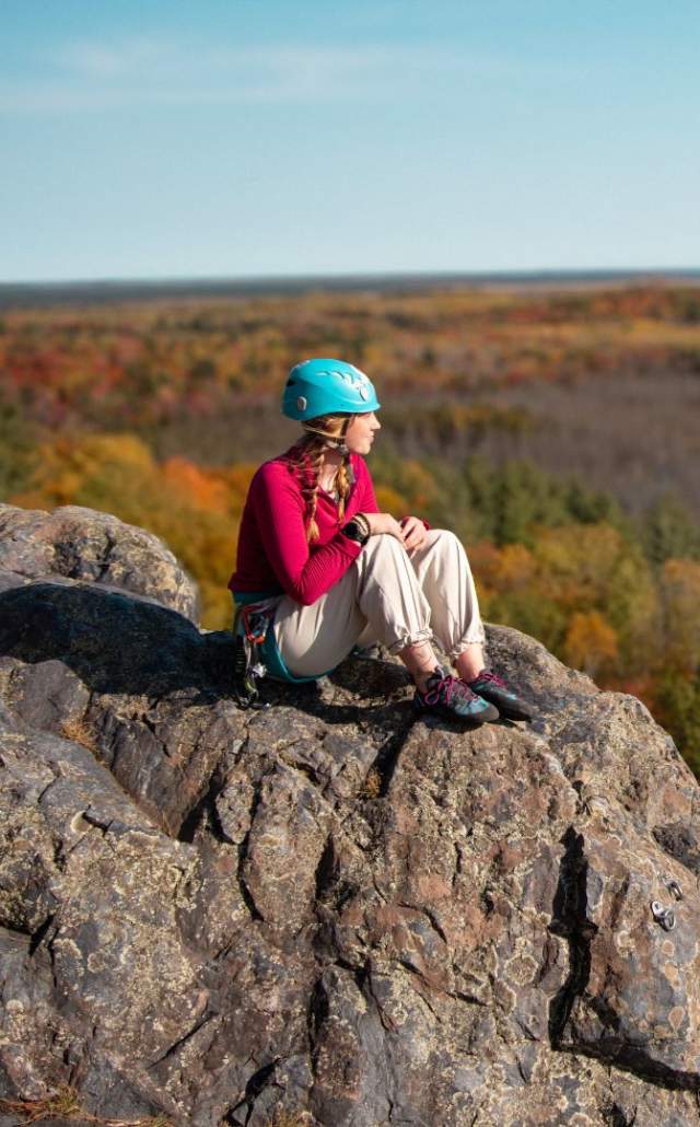 A woman on a rocky ledge overlooking fall color in the Upper Peninsula of Michigan