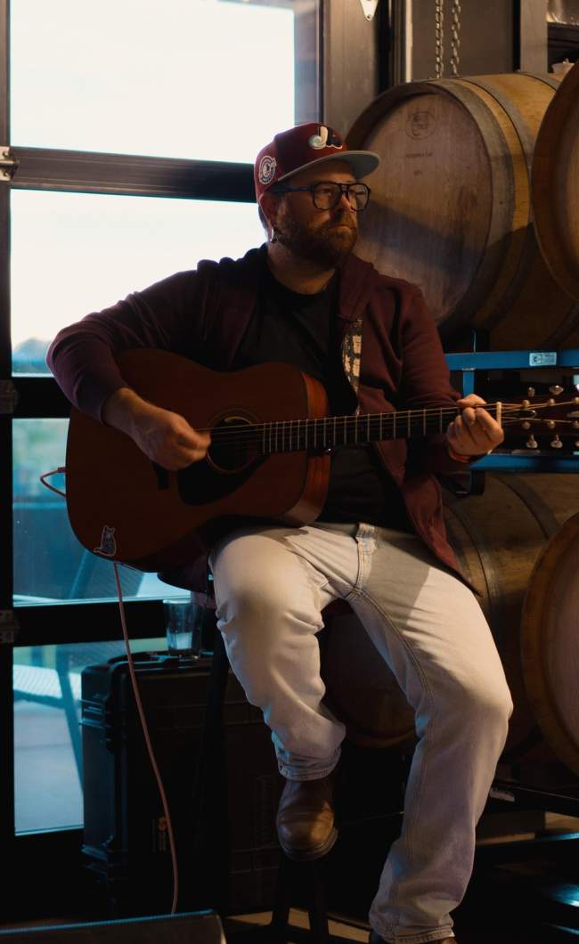 Small band playing in front of a window and wine barrels