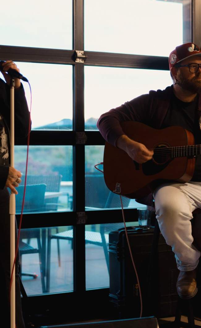 Small band playing in front of a window and wine barrels