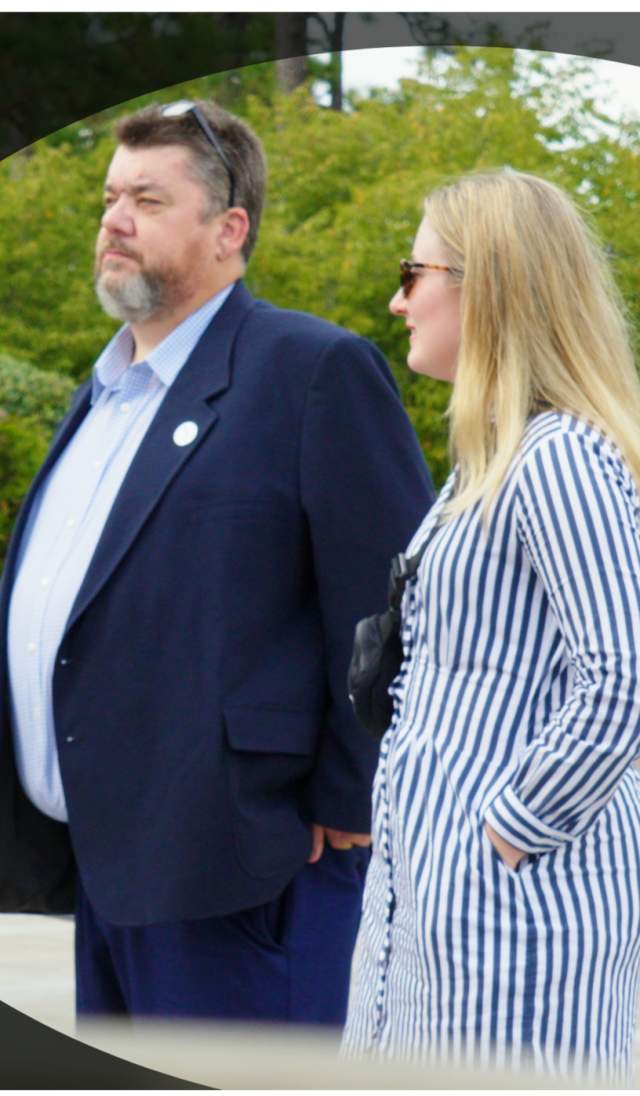 Two people standing outdoors in conversation, shown through a circular spotlight effect with a blurred background