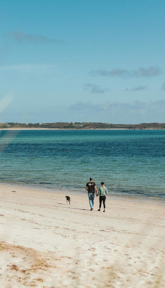 Couple walking along a beach in autumn