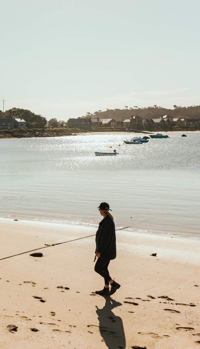 Woman walking along beach with dog
