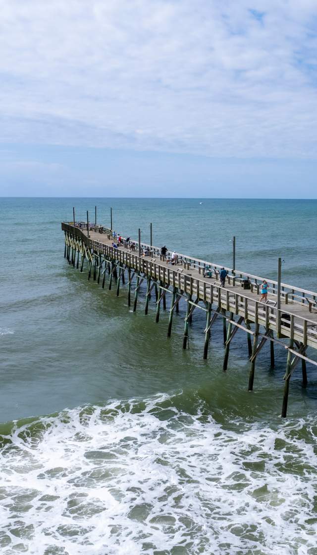 an aerial view of an ocean pier extending into the water