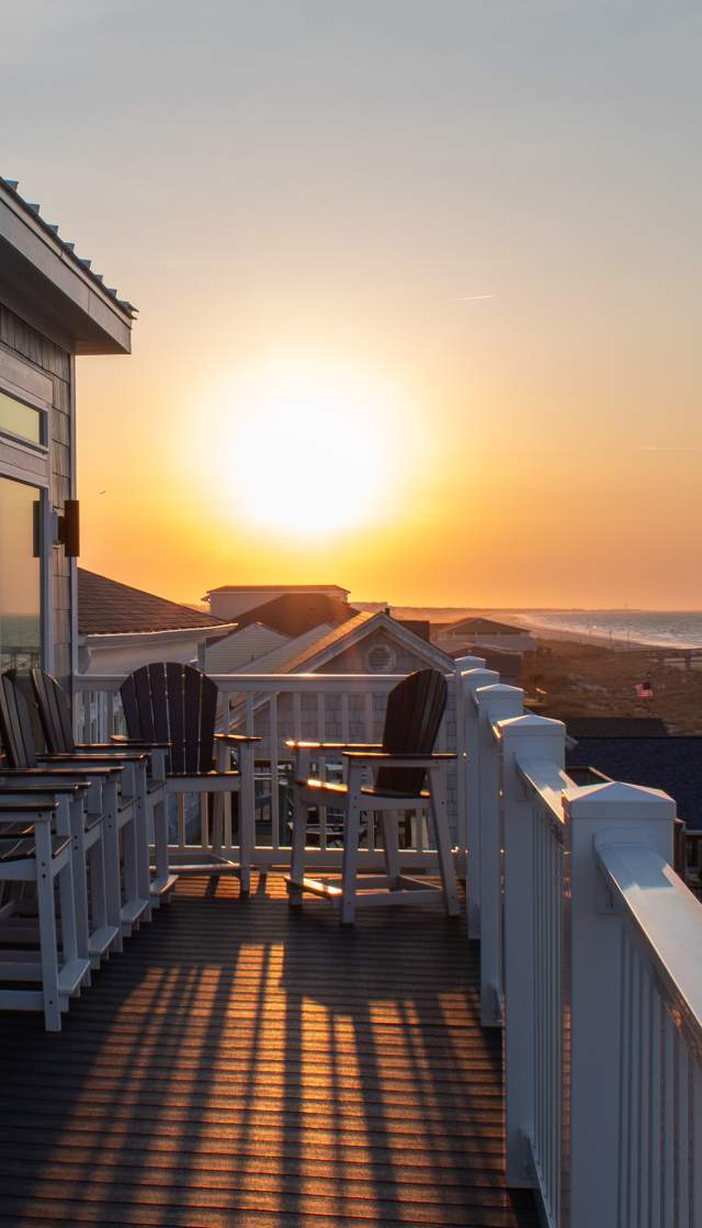 a view of Oak Island and a pier at sunrise from the deck of a vacation rental home