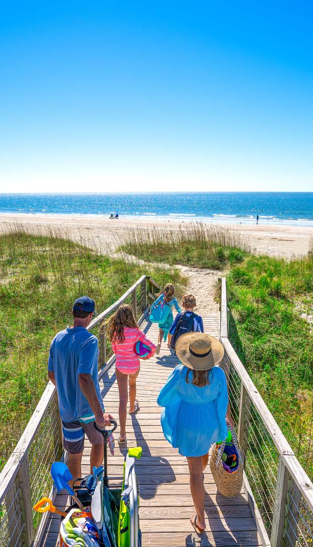 a family of 4 walking out to the beach on a wooden beach access