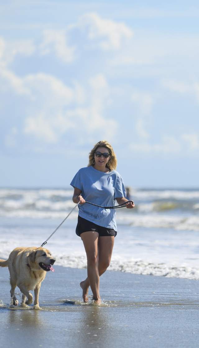 woman walking dog on the beach
