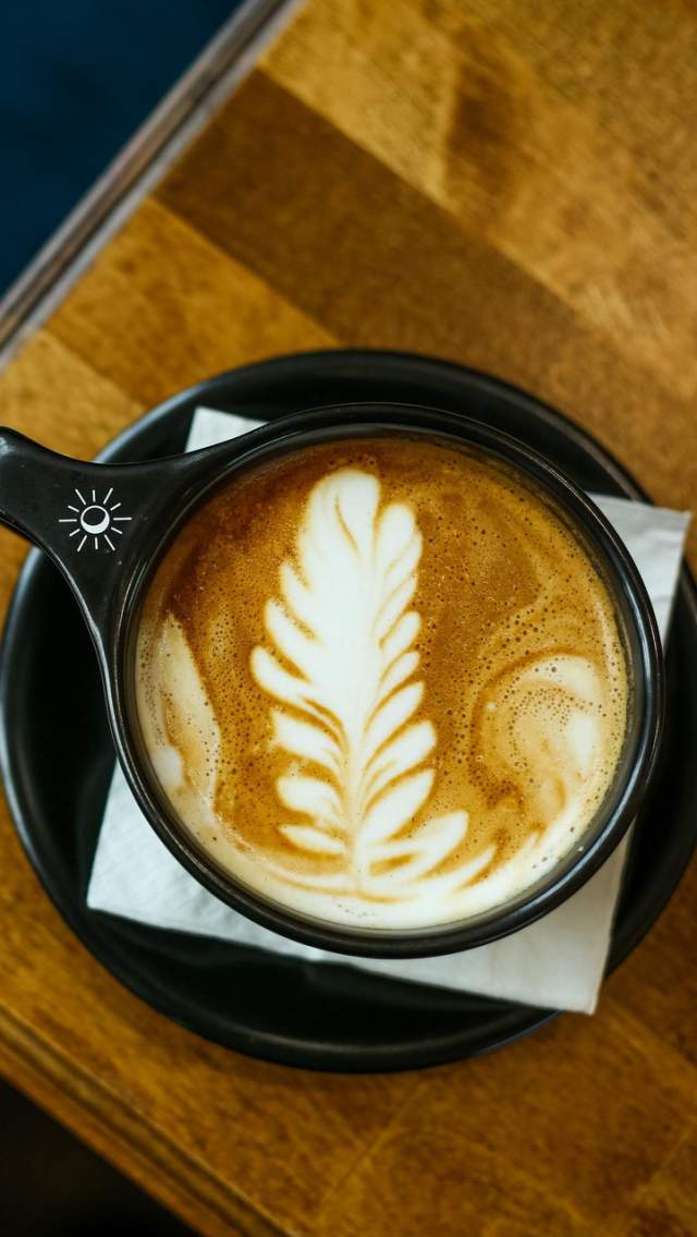 Overhead view of a latte with leaf-shaped foam art in a black cup at Tandem Coffee & Cocktails in Mandeville.
Caption: Latte art takes center stage at Tandem Coffee & Cocktails in Mandeville.