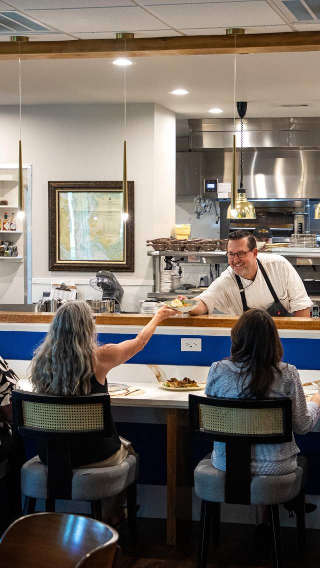 Executive Chef Ryan Gall serves a dish to a tour group seated at the kitchen counter at The Hampshire in downtown Covington.