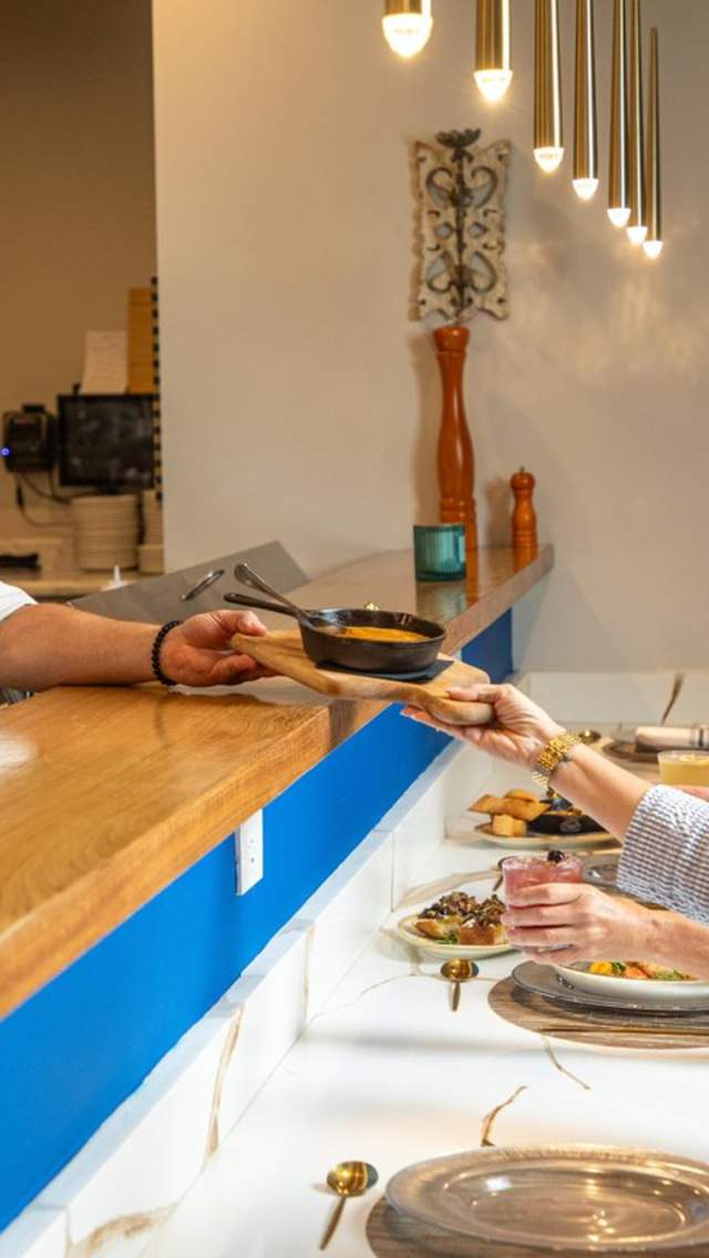 Chef serving a guest at the kitchen-view table at The Hampshire in Covington.