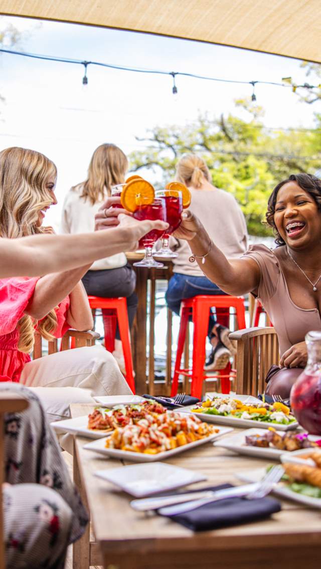 A group of 3 women clinking glasses and enjoying a meal at Valencia restaurant in Covington.